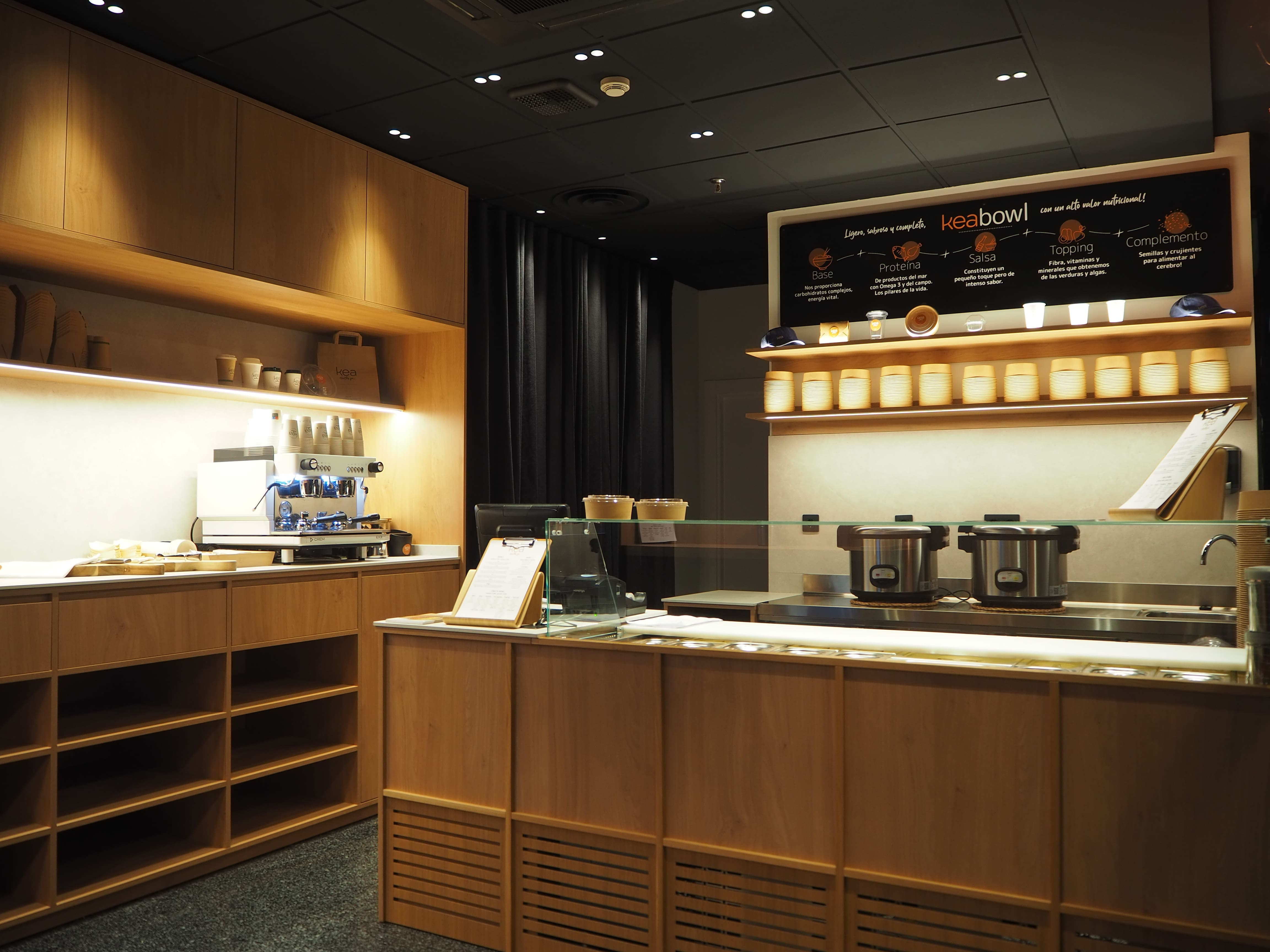 Interior moderno y elegante del restaurante Kea Healthy for con máquina de café y menú visible.
