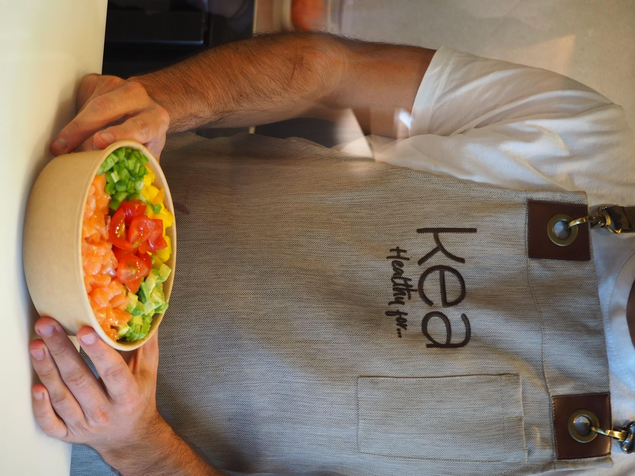 Empleado de Kea Healthy for presentando un bowl de salmón y vegetales frescos